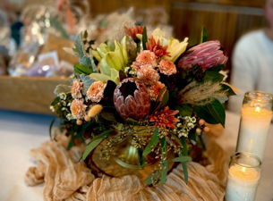 A vibrant floral centerpiece with protea and greenery sits on a table with candles in McLennan County, Texas.