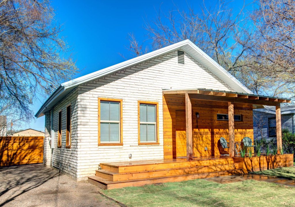 A renovated white brick house with wood siding and a wooden porch in McLennan County, Texas.