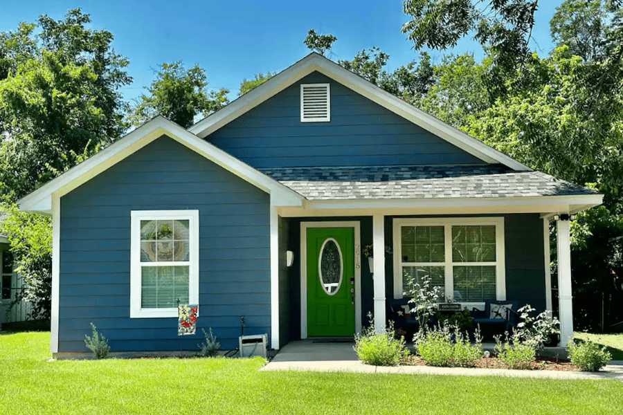 A blue house with a bright green front door and a green lawn in McLennan County, Texas.