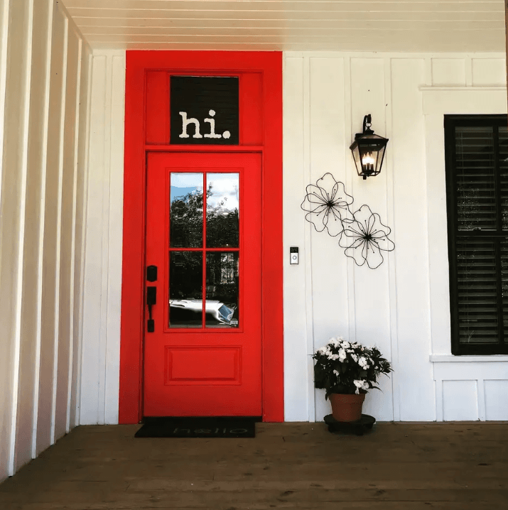 A bright red front door with a hi sign on a white porch in McLennan County, Texas.