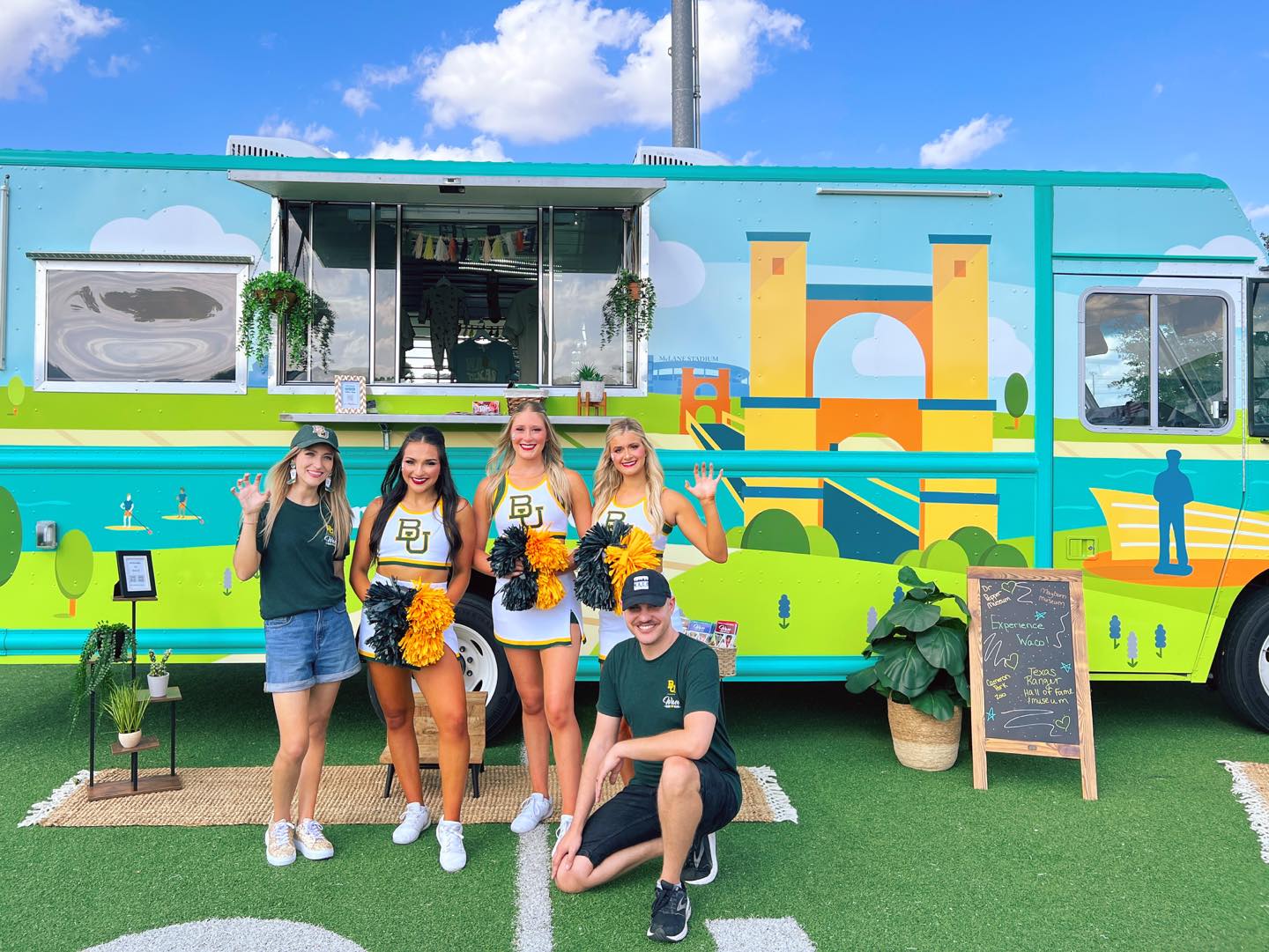 A group of people posing in front of a colorful Baylor University branded food truck in McLennan County, Texas.