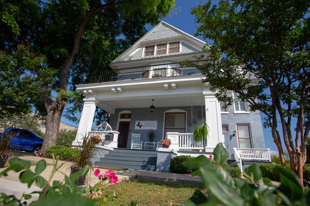 A charming grey historic house with a large front porch and white trim in McLennan County, Texas.