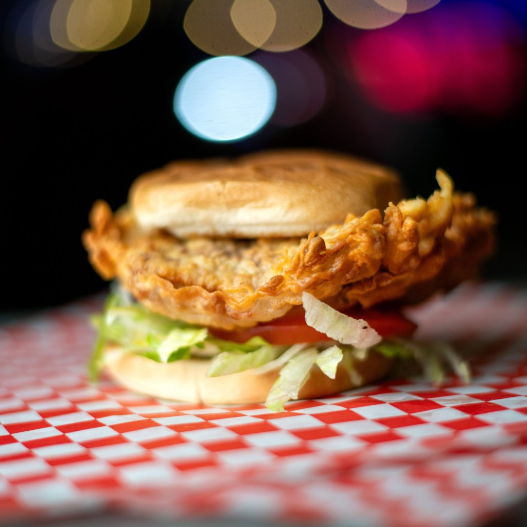A crispy fried chicken sandwich on a red and white checkered paper from Lefty's in Hewitt, Texas.