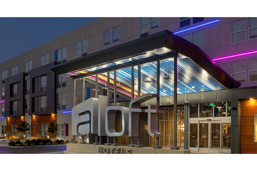 The exterior of an Aloft hotel building at dusk with colorful neon lighting in McLennan County, Texas.