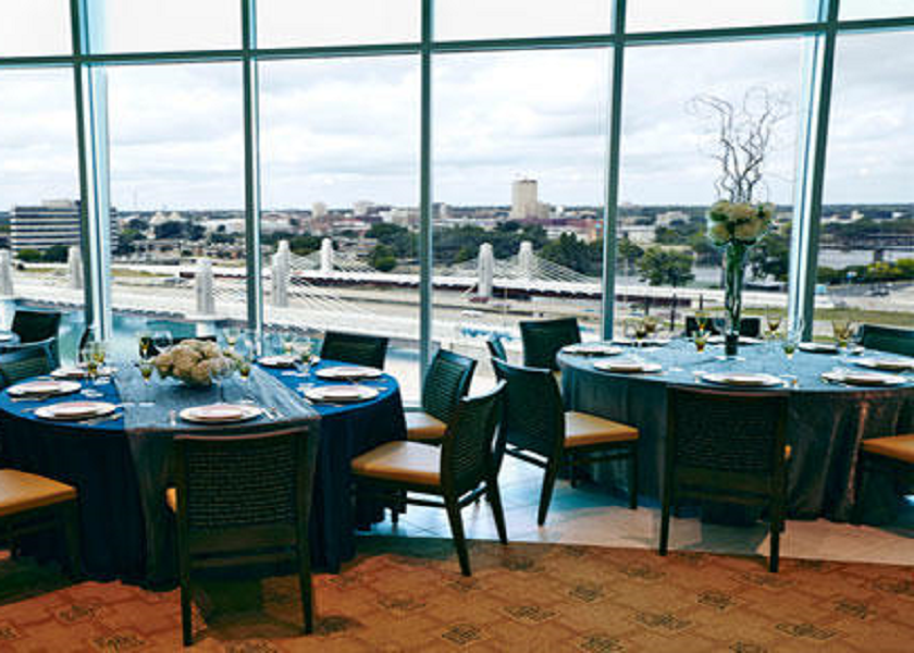 A banquet room with round tables overlooking a city skyline and a bridge in McLennan County, Texas.
