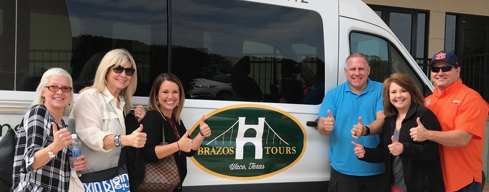 A group of six people giving thumbs up in front of a Brazos Tours van in McLennan County, Texas.