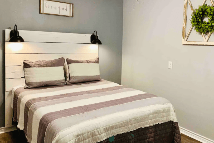 A cozy bedroom featuring a white shiplap headboard and a striped quilt in McLennan County, Texas.
