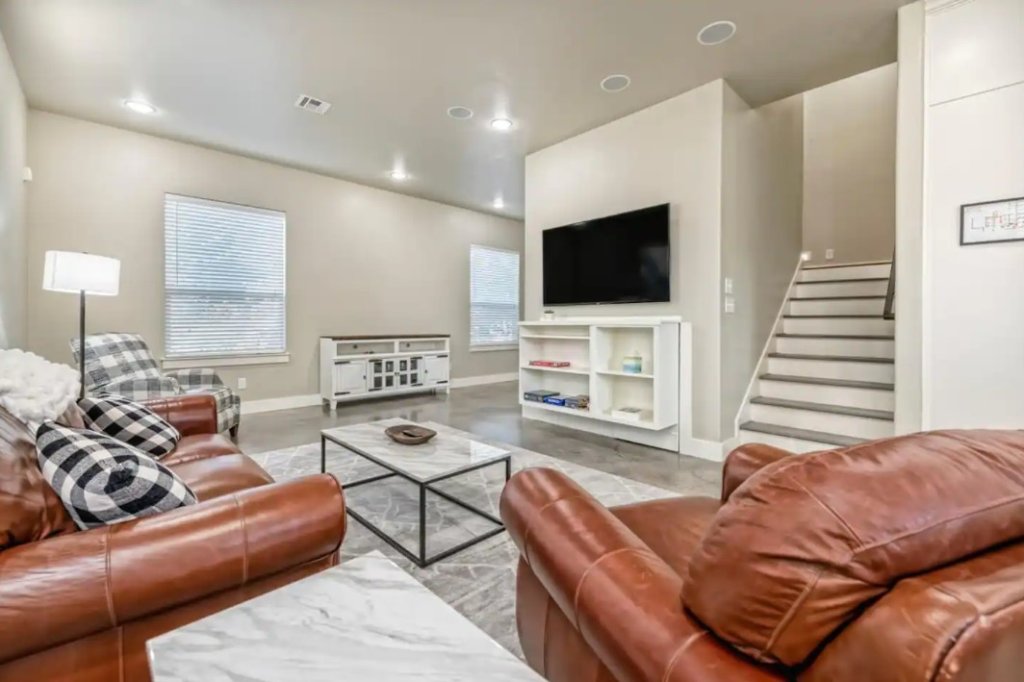 A modern living room featuring brown leather furniture and a wall-mounted television in McLennan County, Texas.