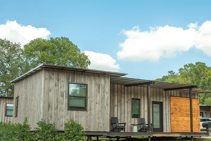 A modern cabin with wood siding and a metal roof under a blue sky in McLennan County, Texas.