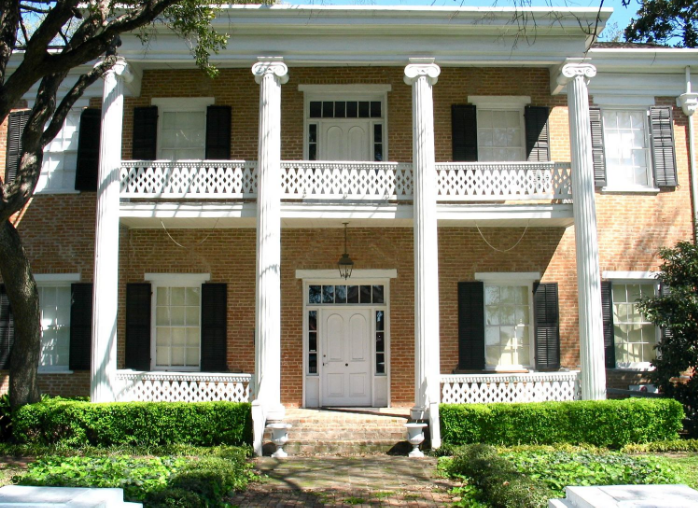 A two-story brick house with white columns and a balcony in McLennan County, Texas.