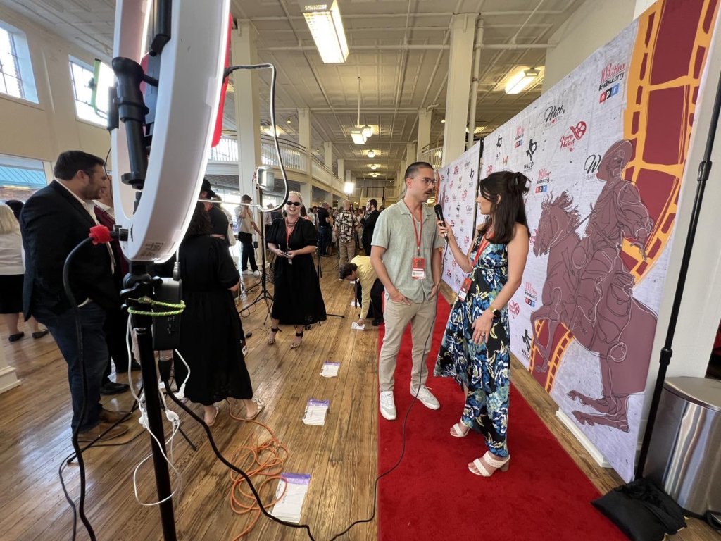 A woman interviewing a man on a red carpet at an event in McLennan County, Texas.