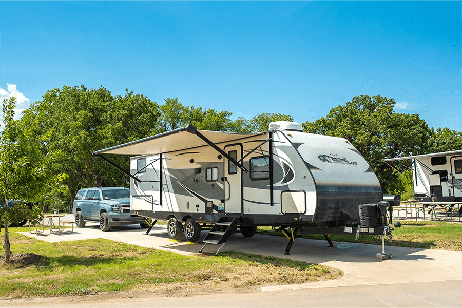 A travel trailer parked at a campsite with a blue SUV parked alongside in McLennan County, Texas.