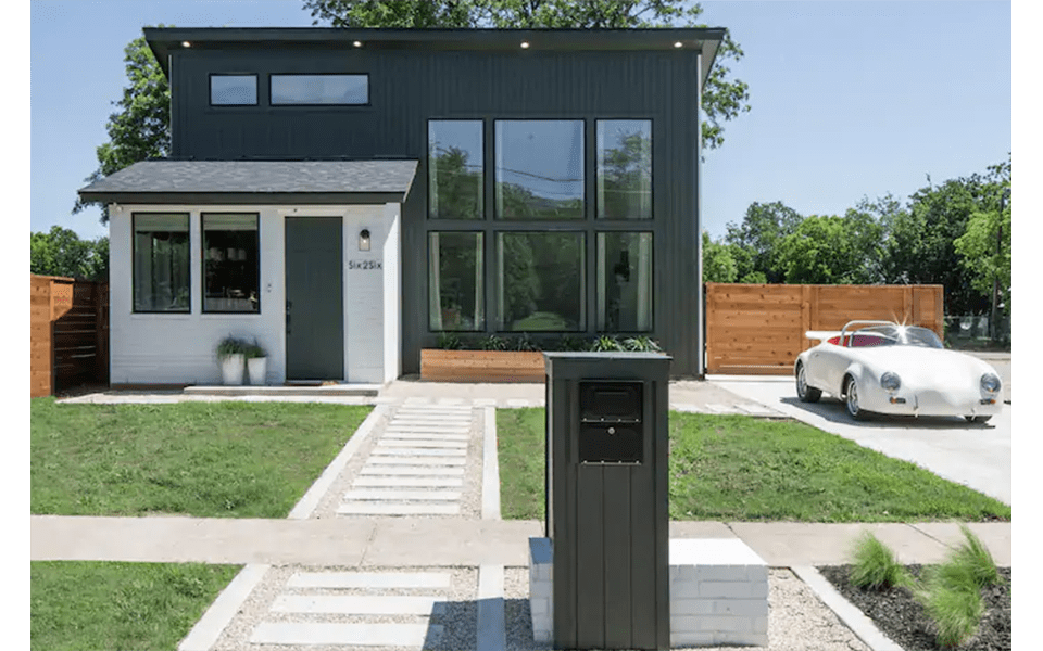 A modern house with a white and dark grey exterior and a vintage car parked in McLennan County, Texas.