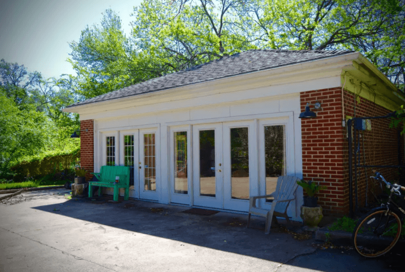 A brick building with white trim and glass doors sits in a wooded area in McLennan County, Texas.