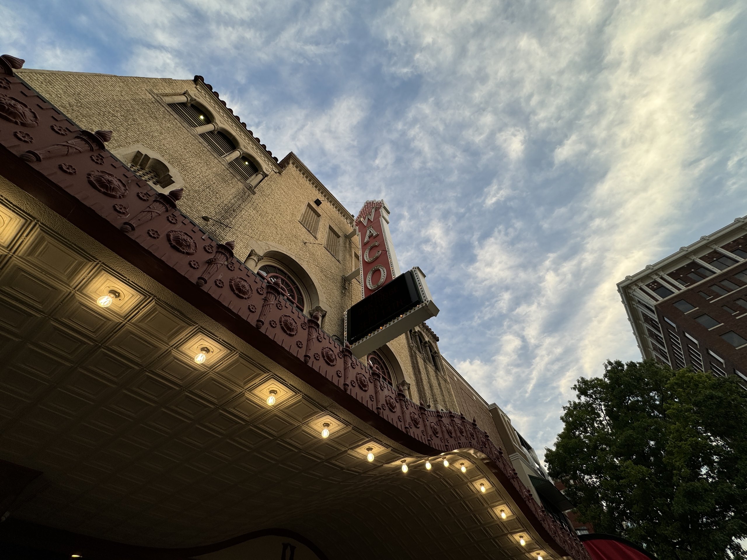 A low-angle view of the historic Waco Hippodrome Theatre marquee against a cloudy sky in McLennan County, Texas.