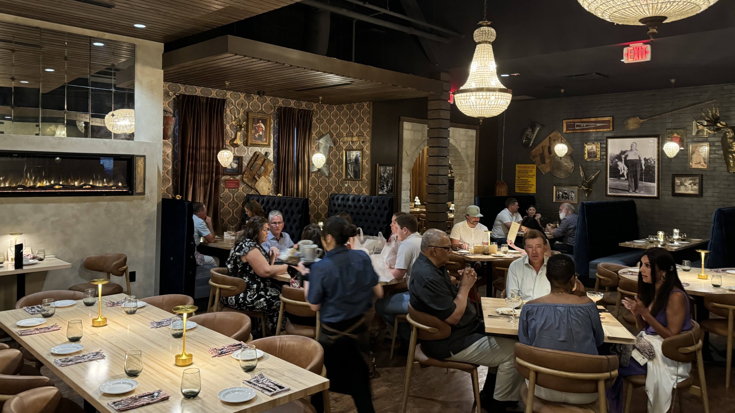 A busy, dimly lit restaurant with elegant decor, chandeliers, and patrons dining at tables in McLennan County, Texas.