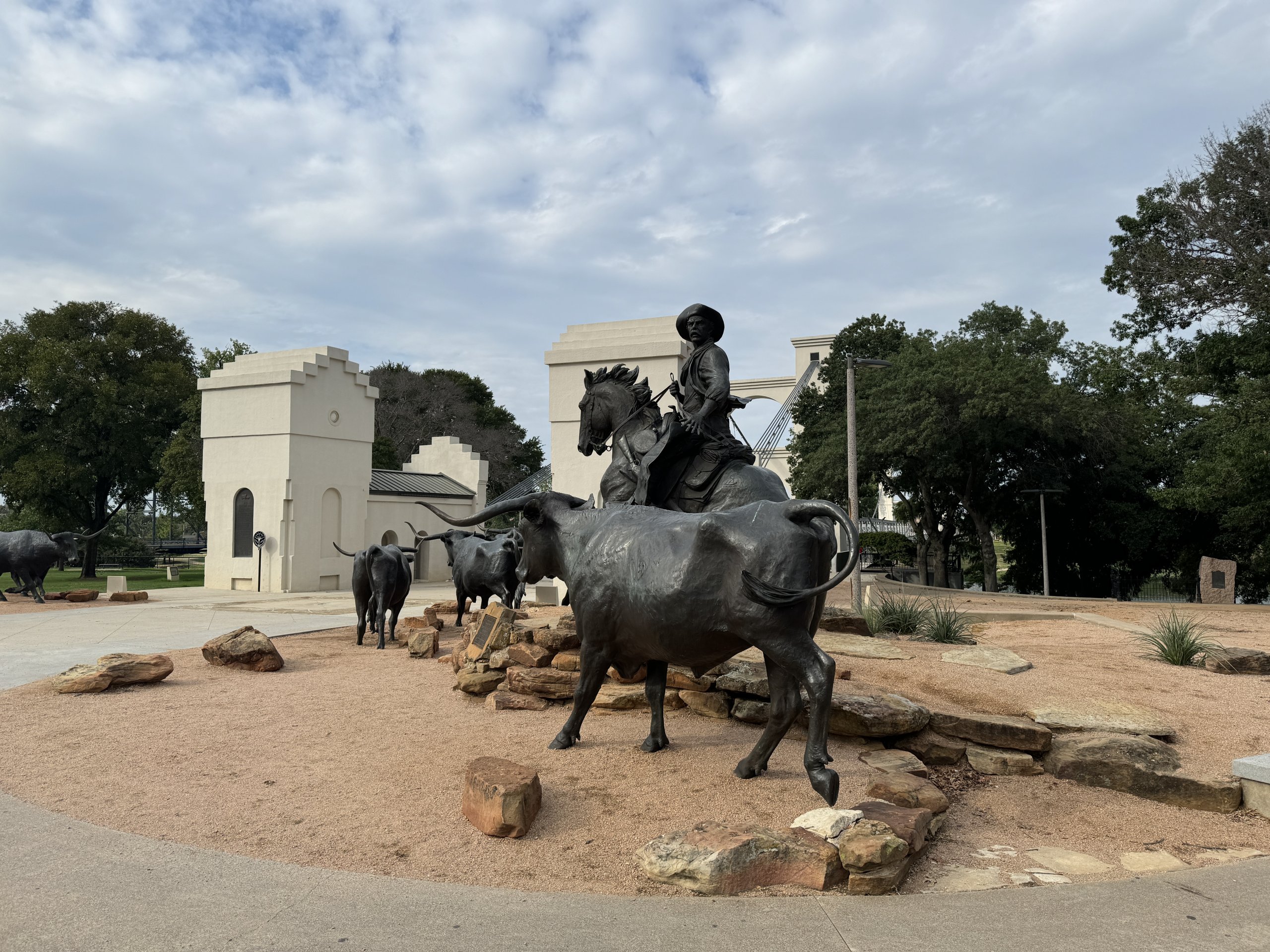 Bronze statues of a cowboy on horseback driving a herd of longhorn cattle in McLennan County, Texas.