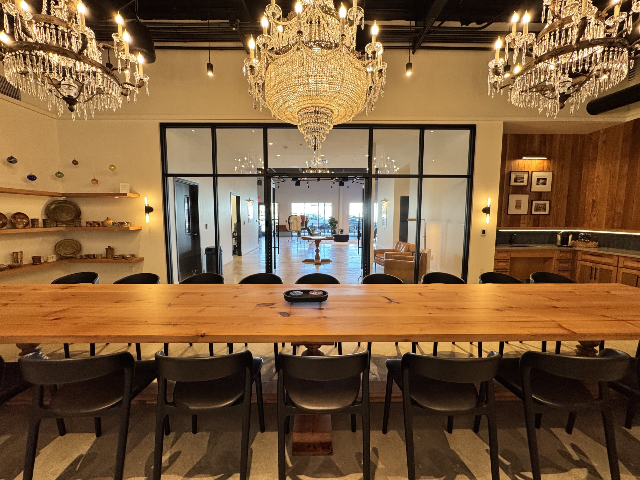 A long wooden table with black chairs under large crystal chandeliers in a room in McLennan County, Texas.