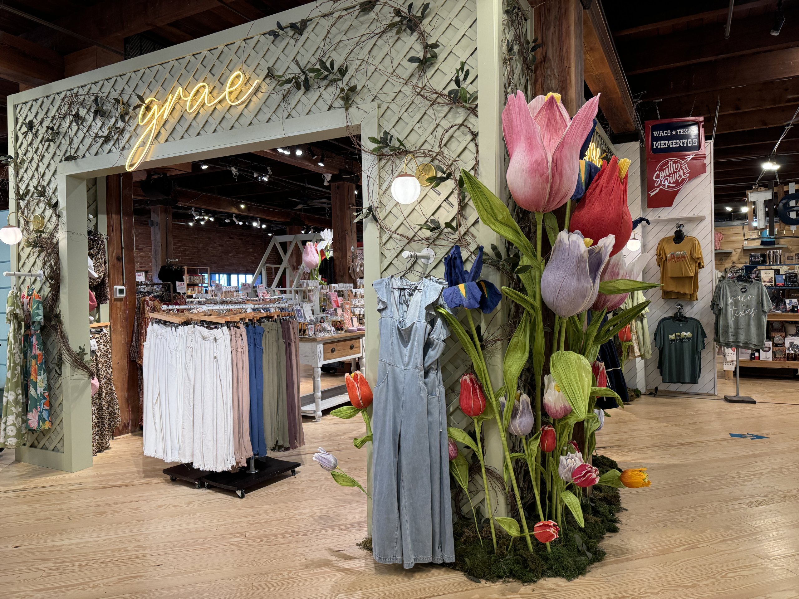 A boutique clothing store entrance decorated with large artificial flowers and a neon sign in McLennan County, Texas.