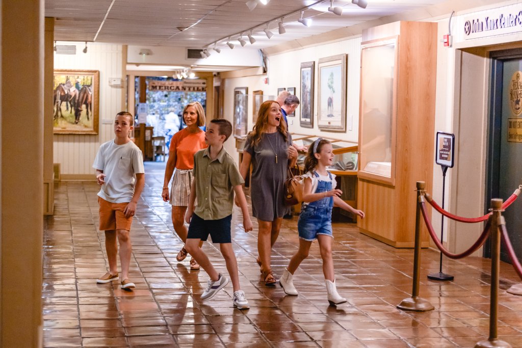 A family walks through a museum hallway with paintings and exhibits on display in McLennan County, Texas.