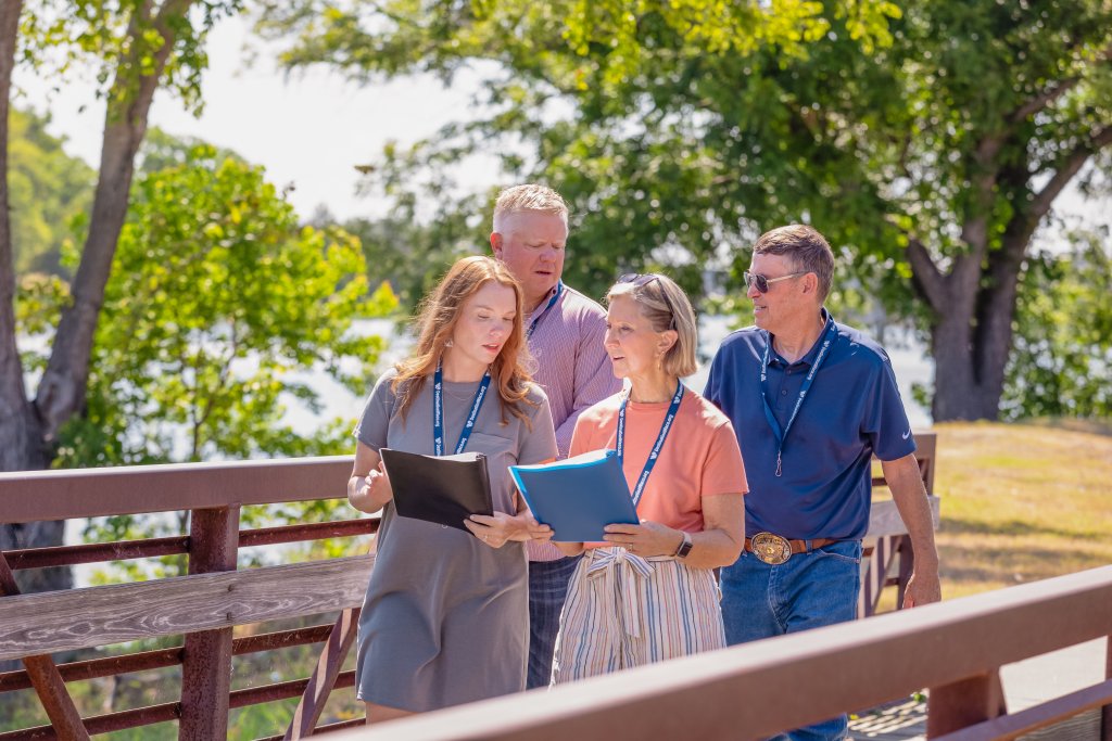 Four people walking on a bridge while reviewing documents outdoors in McLennan County, Texas.