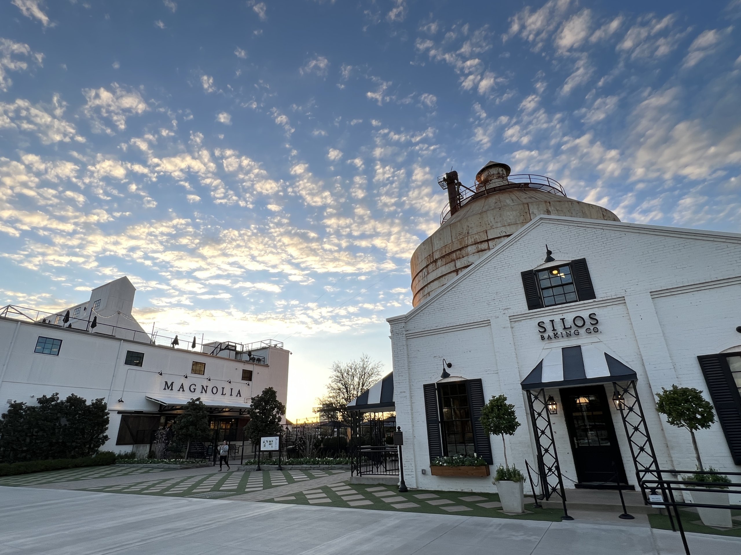A view of the Silos Baking Co. and Magnolia buildings under a cloudy sunset sky in McLennan County, Texas.