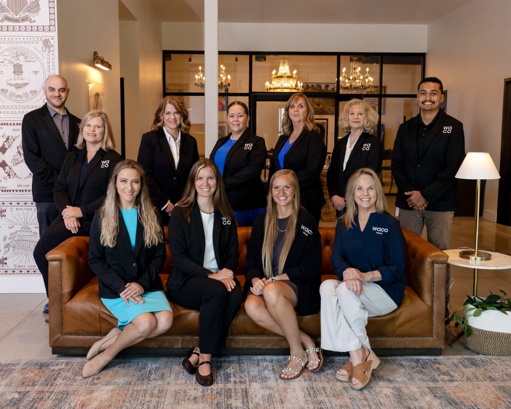 A group of eleven professional men and women posing for a portrait in an office in McLennan County, Texas.
