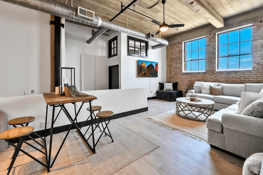 A modern industrial-style living room with exposed brick, ductwork, and a cozy seating area in McLennan County, Texas.