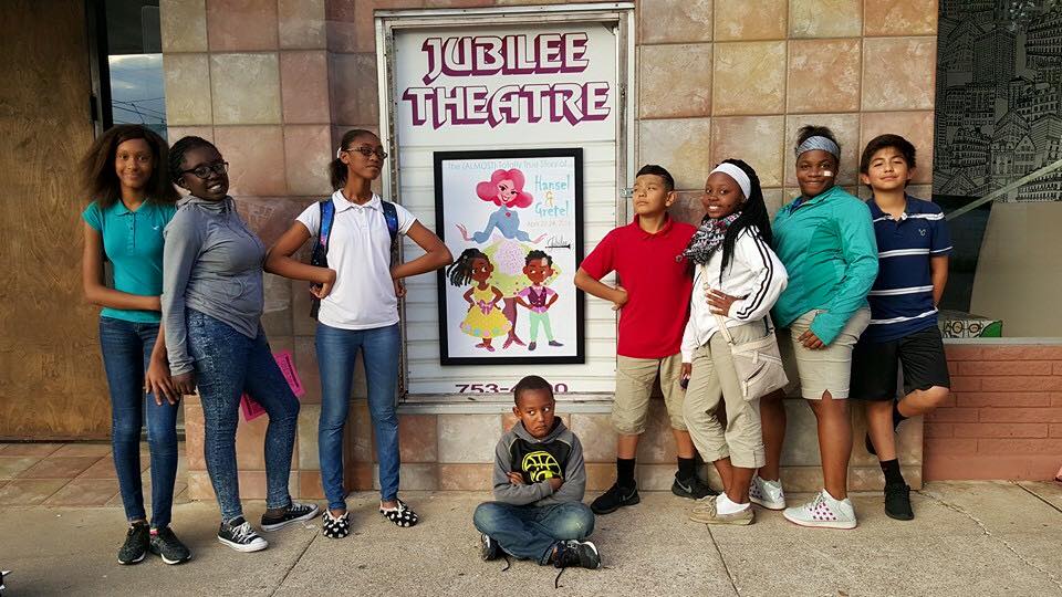 A group of diverse children posing in front of the Jubilee Theatre entrance in McLennan County, Texas.
