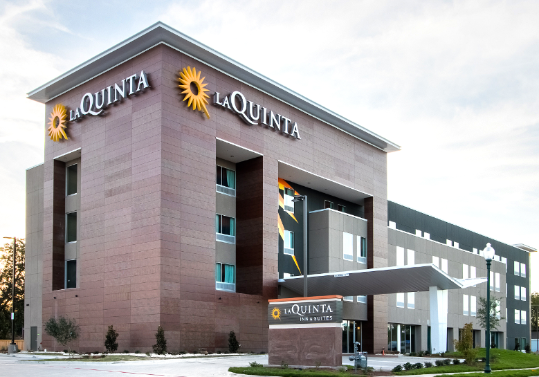 A modern La Quinta Inn and Suites hotel building with a prominent entrance sign in McLennan County, Texas.
