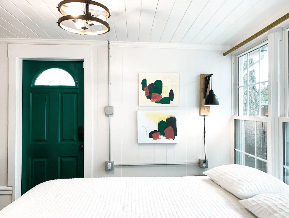 A bedroom with white walls, a green door, and two abstract paintings in McLennan County, Texas.