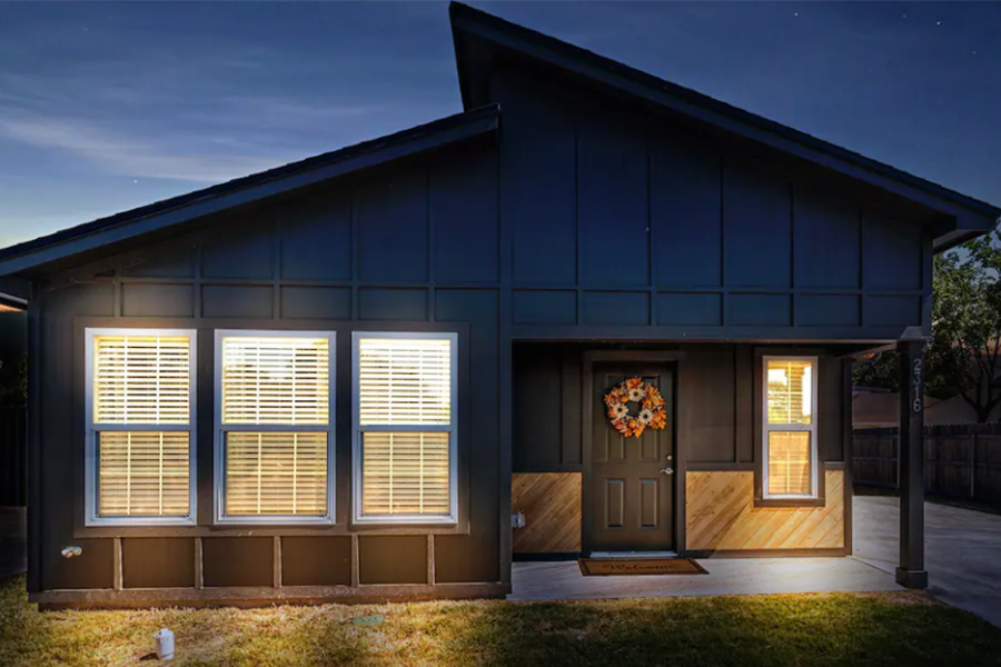 A modern dark-painted house with wood accents at night in McLennan County, Texas.