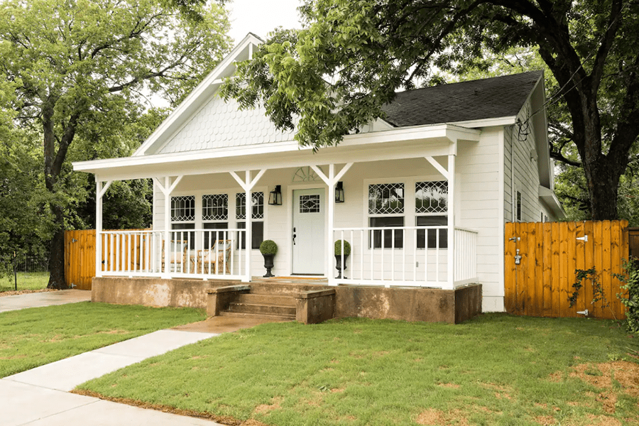 A charming white cottage with a front porch and wooden fence in McLennan County, Texas.