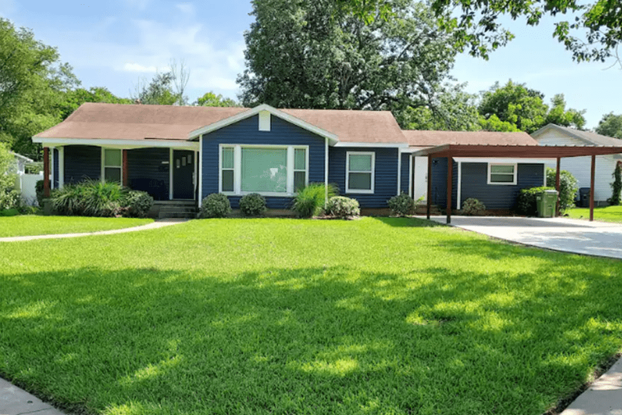 A blue single-story house with a brown roof and a carport in McLennan County, Texas.