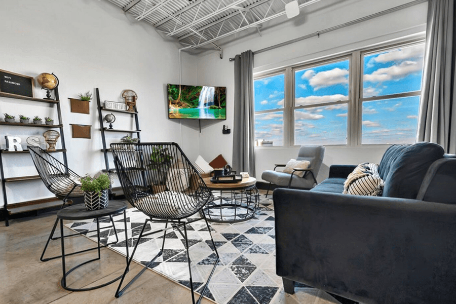 A modern living room with industrial decor, black wire chairs, and a large window in McLennan County, Texas.