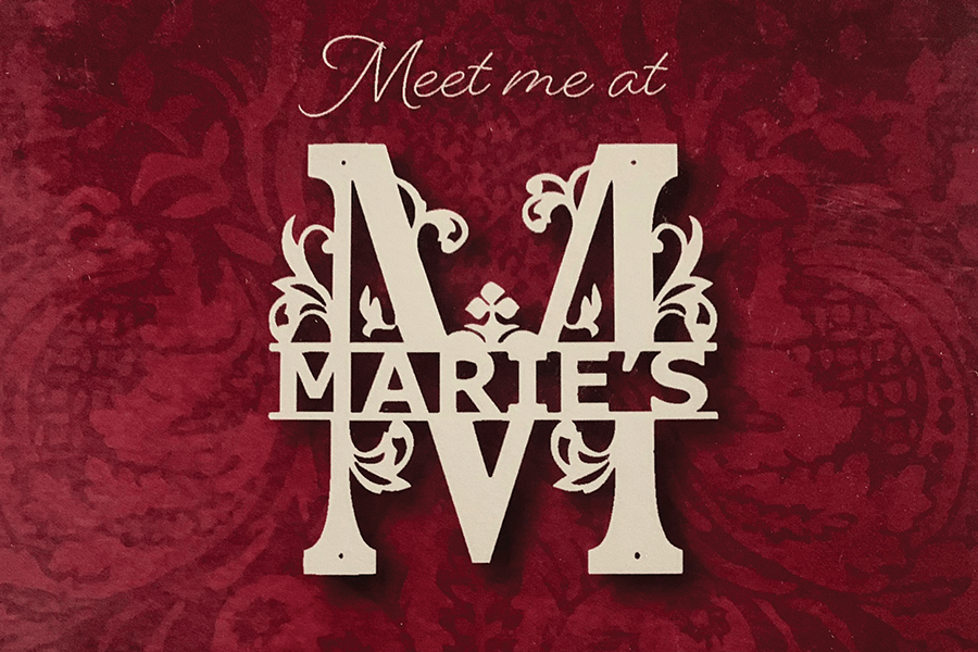 A decorative sign reading Meet me at Marie's against a dark red patterned background in McLennan County, Texas.