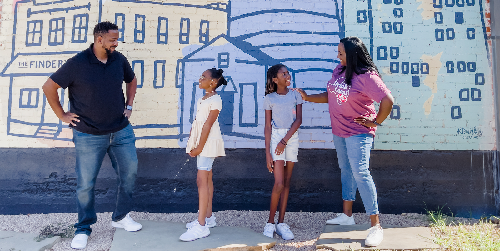 A family of four standing in front of a colorful building mural in McLennan County, Texas.