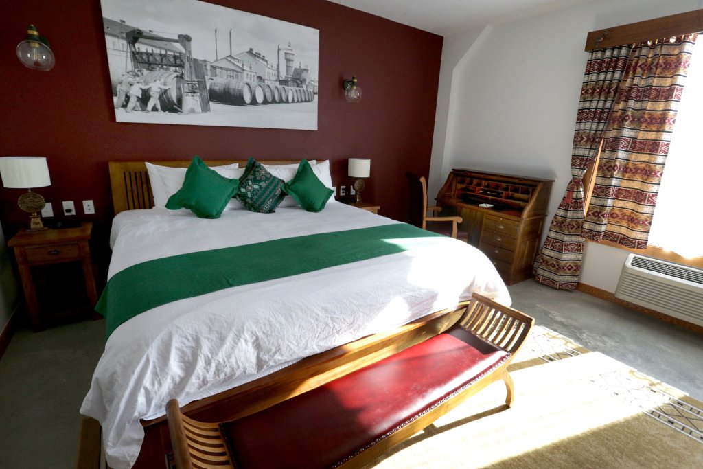 A hotel room with a large bed, green accents, and a vintage wall print in McLennan County, Texas.