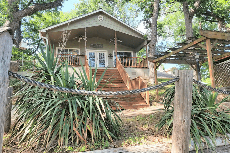 A small cabin with a wooden staircase and porch surrounded by trees in McLennan County, Texas.