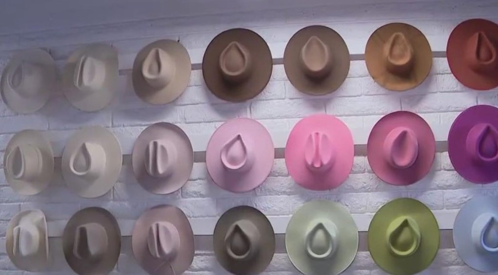 A collection of colorful felt hats displayed on a white brick wall in McLennan County, Texas.