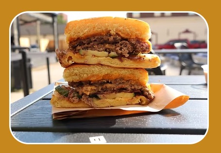 A halved cheeseburger sits on a piece of paper on a dark table in McLennan County, Texas.