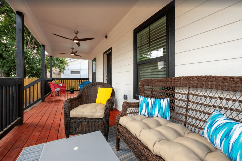 A covered porch with wicker furniture, a red wooden floor, and ceiling fans in McLennan County, Texas.