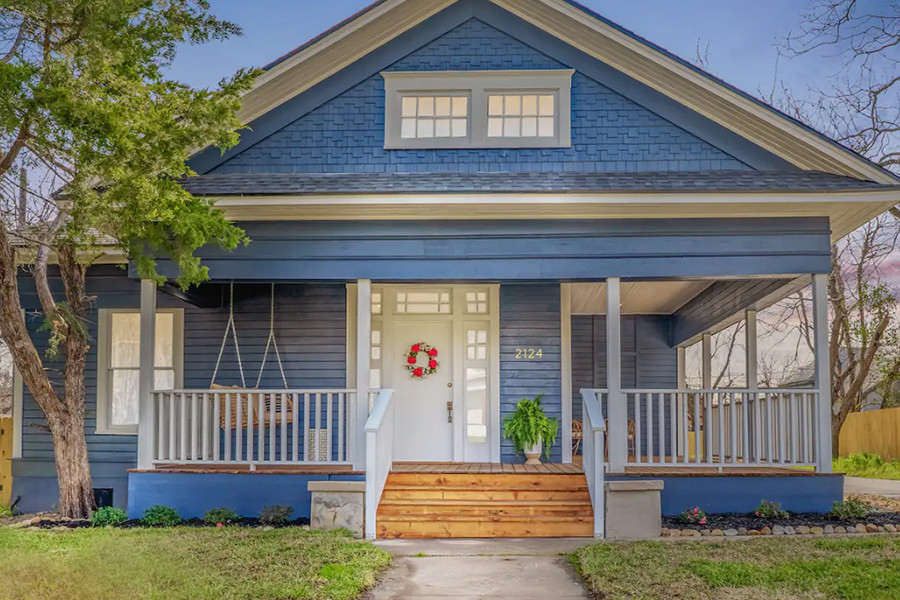 A blue craftsman-style house with a front porch and a white door in McLennan County, Texas.