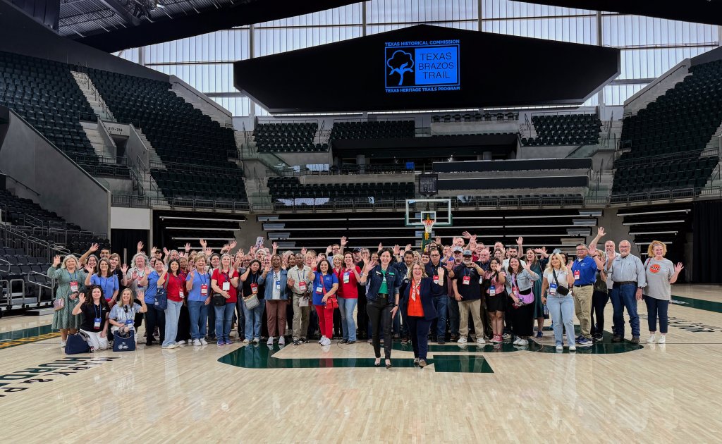 A large group of people posing for a photo on a basketball court in McLennan County, Texas.