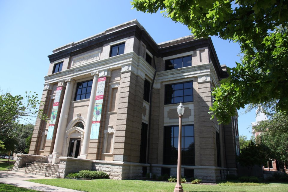 A historic brick building with white columns and banners under a clear blue sky in McLennan County, Texas.