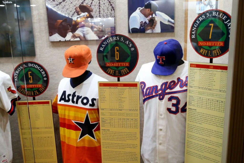 A museum display case featuring baseball jerseys, caps, and no-hitter commemorative signs in McLennan County, Texas.