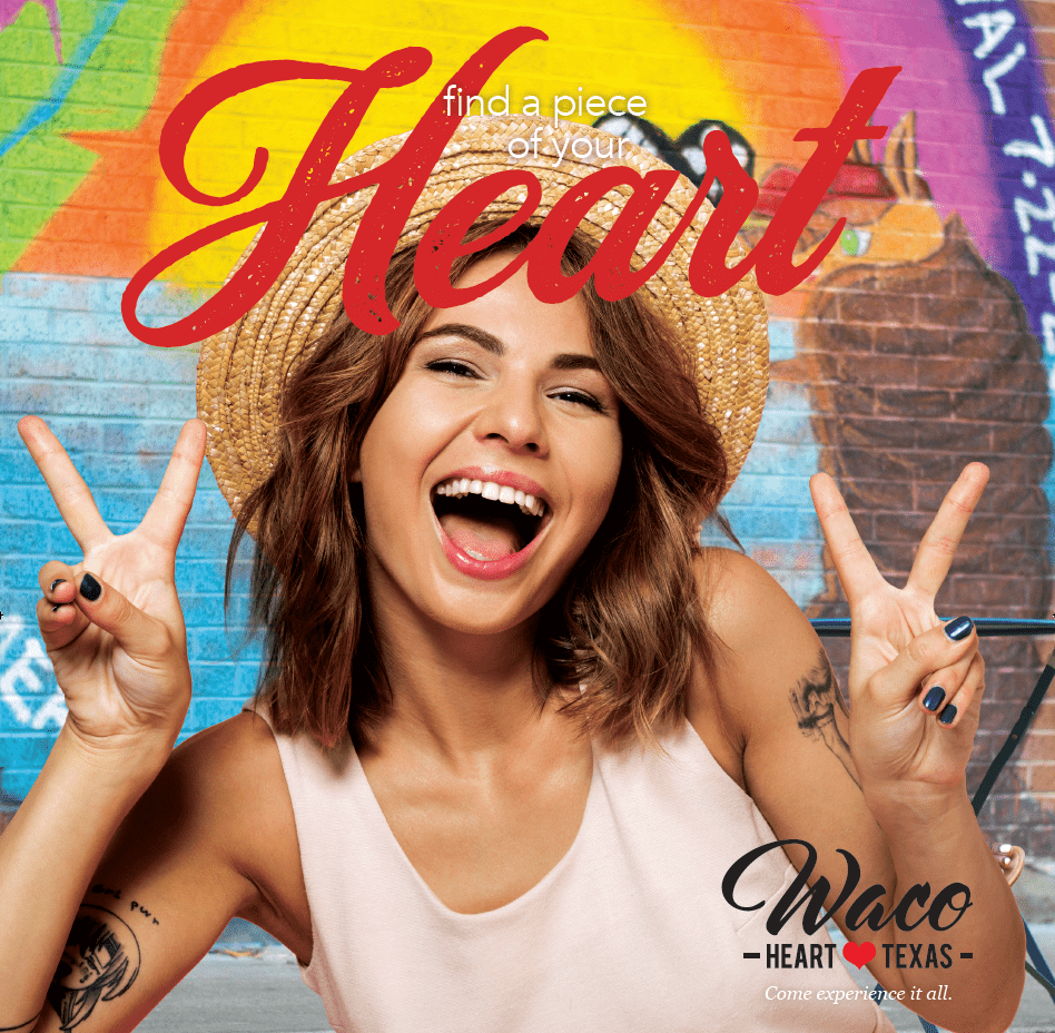 A smiling woman in a straw hat makes peace signs in front of graffiti in McLennan County, Texas.
