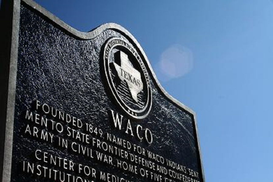 A historical marker sign for Waco, Texas, against a clear blue sky in McLennan County, Texas.