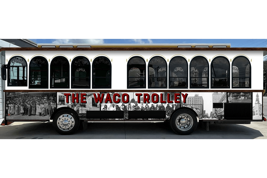 A side view of a white trolley bus labeled The Waco Trolley in McLennan County, Texas.