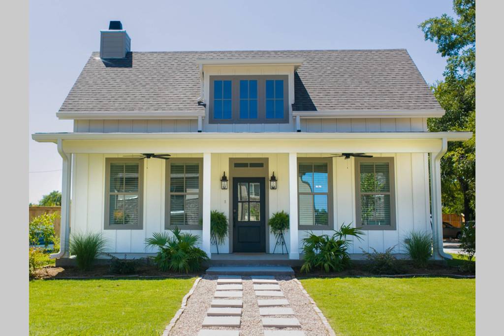 A charming white farmhouse with a front porch and a stone walkway in McLennan County, Texas.